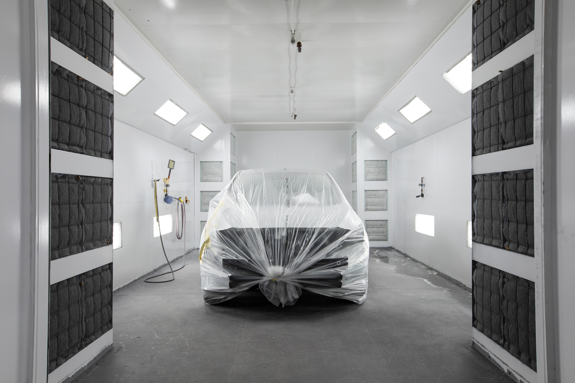 Vehicle fully masked and ready for refinishing inside Crown's paint booth